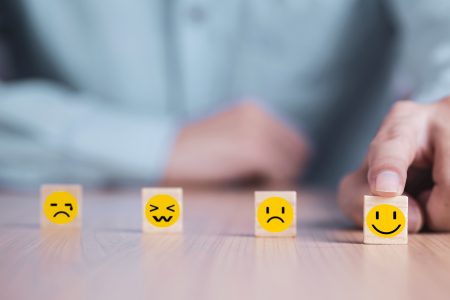 Businessman chooses a smile emoticon icons face happy symbol on wooden block , Services and Customer satisfaction survey concept